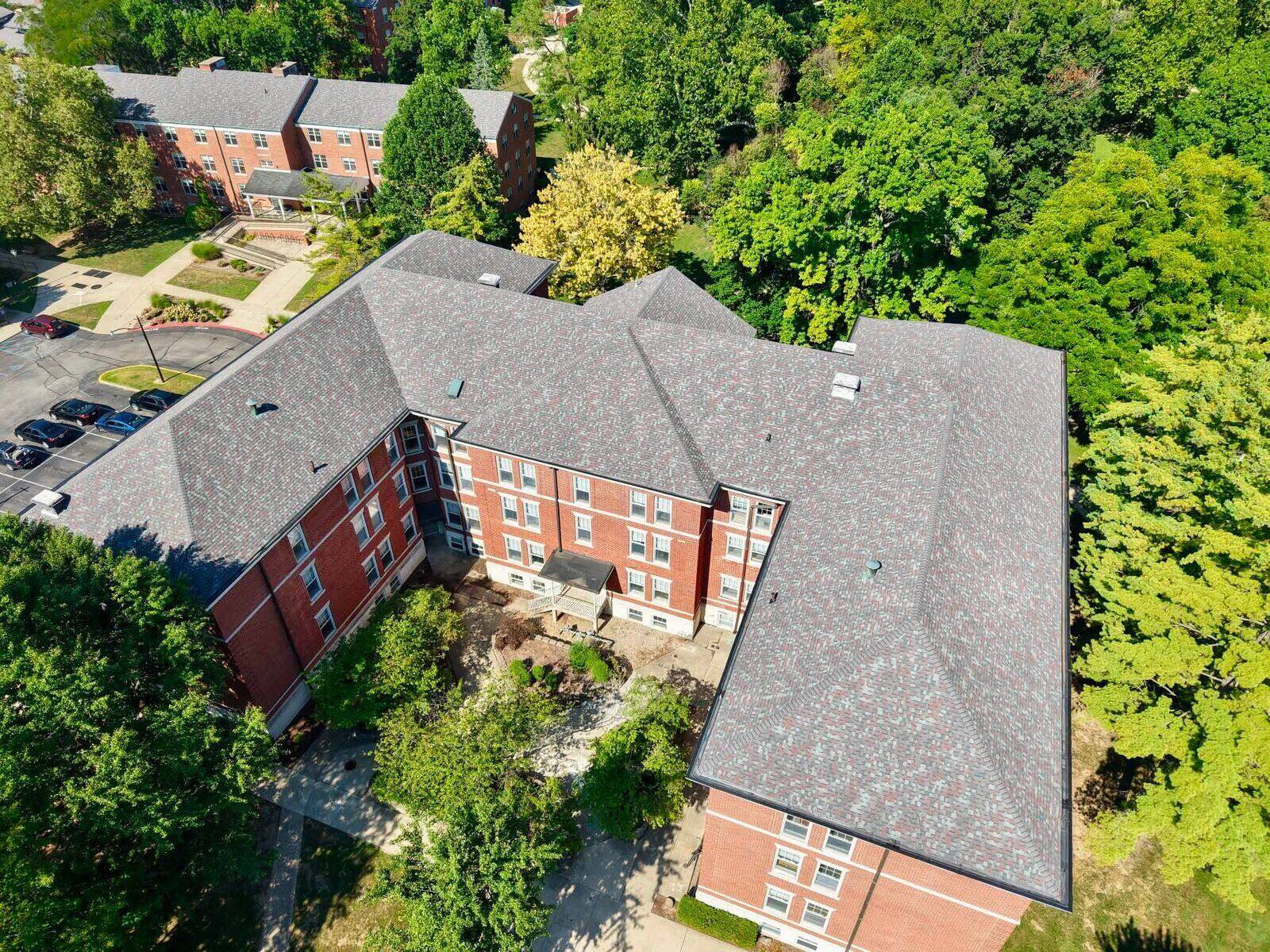 A large multi-story brick institutional building with a new shingle roof.